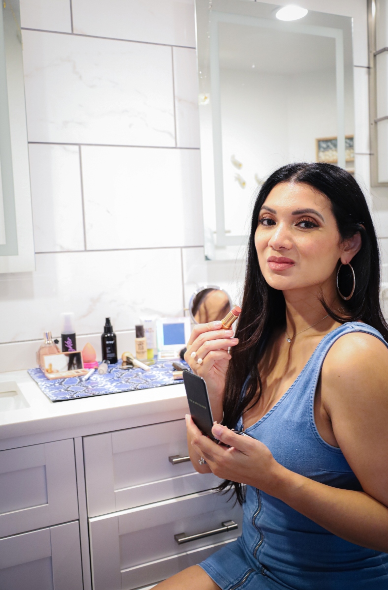 Woman posing in bathroom with lipstick in an organized bathroom