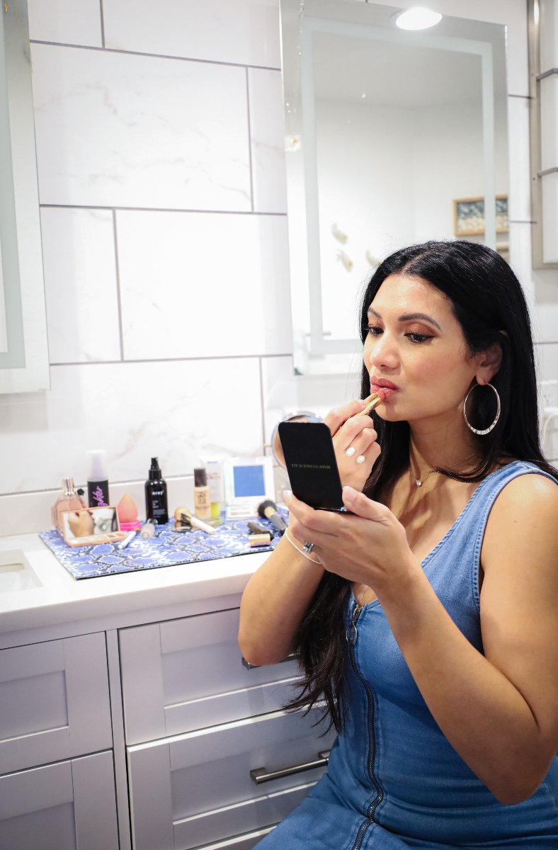 Woman applying lipstick in an organized bathroom